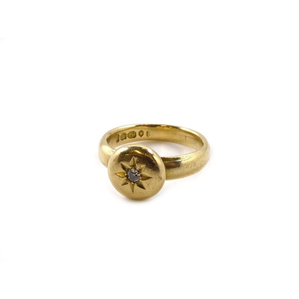 Presenting the Early 20th Century Diamond Set Ring by Hidden Gems: an exquisite 18 carat yellow gold ring showcasing a round, flat top adorned with an engraved star design and a delicate central diamond. The inner band features elegantly engraved text, enhancing its allure. This vintage piece from the 1920s radiates classic elegance and timeless beauty.