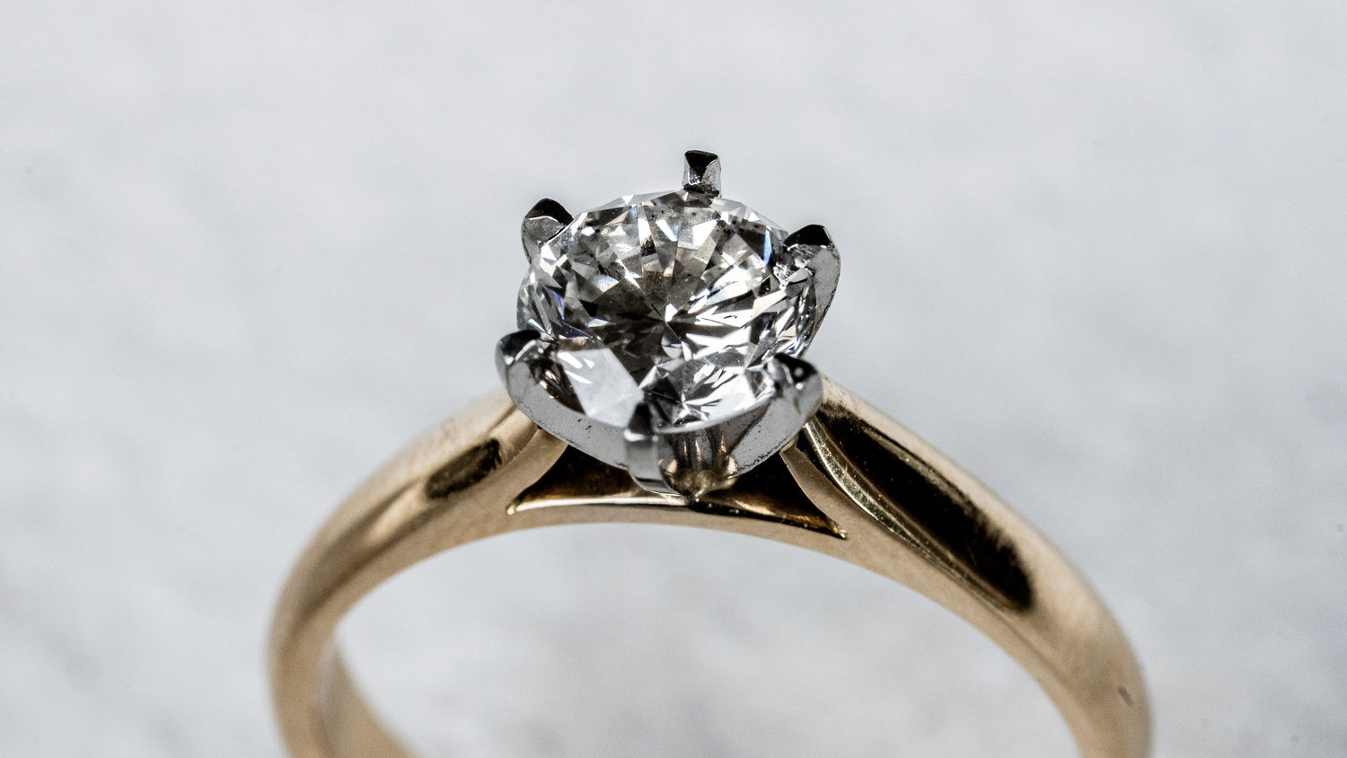 A gold ring with three diamonds is placed on a textured gray stone surface.