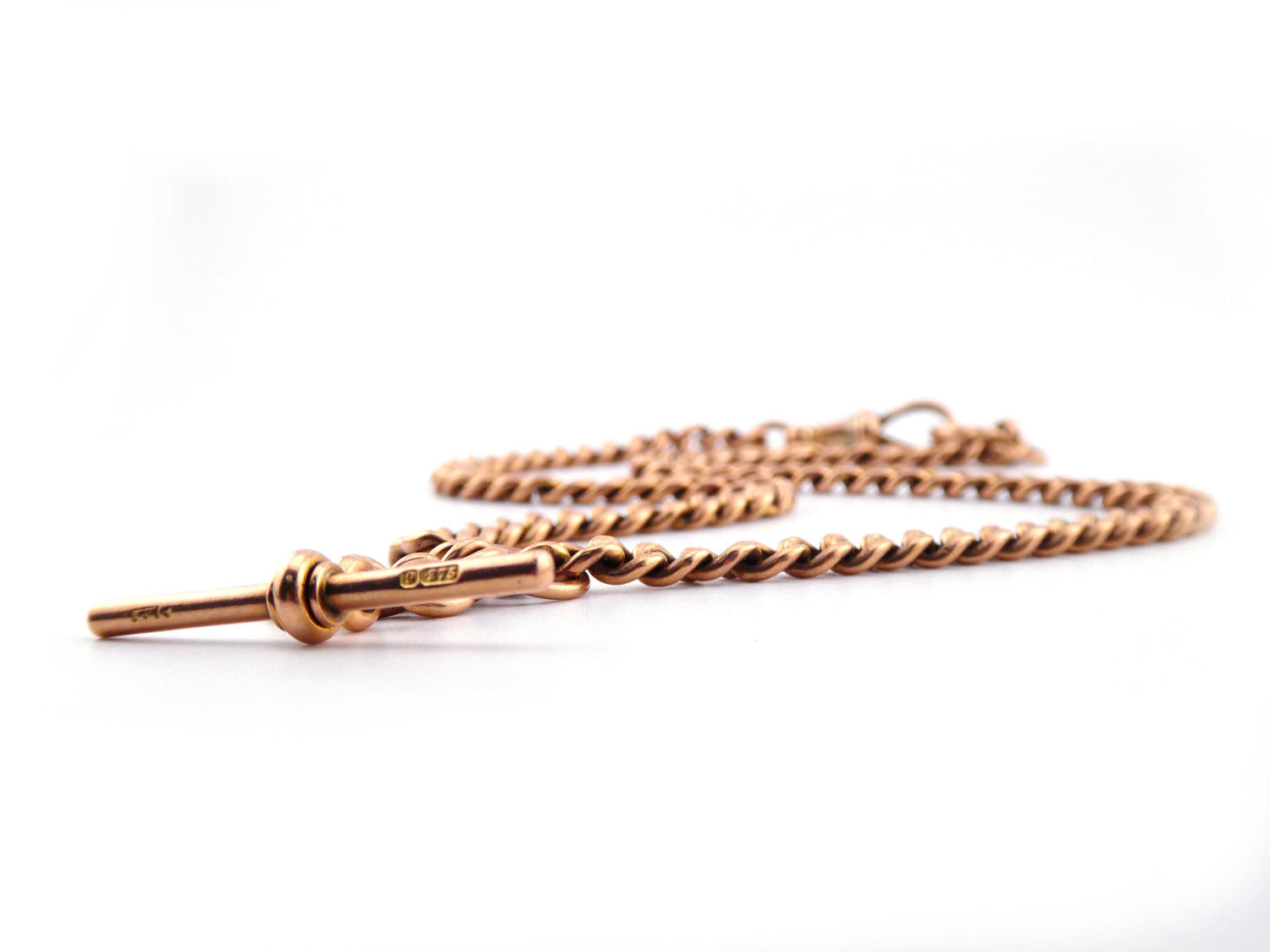 Close-up of an estate 9 carat gold fob chain by Hidden Gems with a sleek, stylized bar pendant against a white background, featuring an elegant albert clasp that evokes timeless 1920s charm.