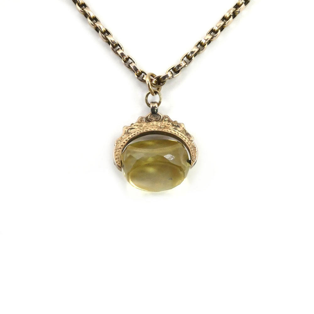 The Victorian Citrine Swivel Pendant and Chain by Hidden Gems is a gold chain necklace with an ornate rose gold pendant featuring a faceted yellow gemstone.